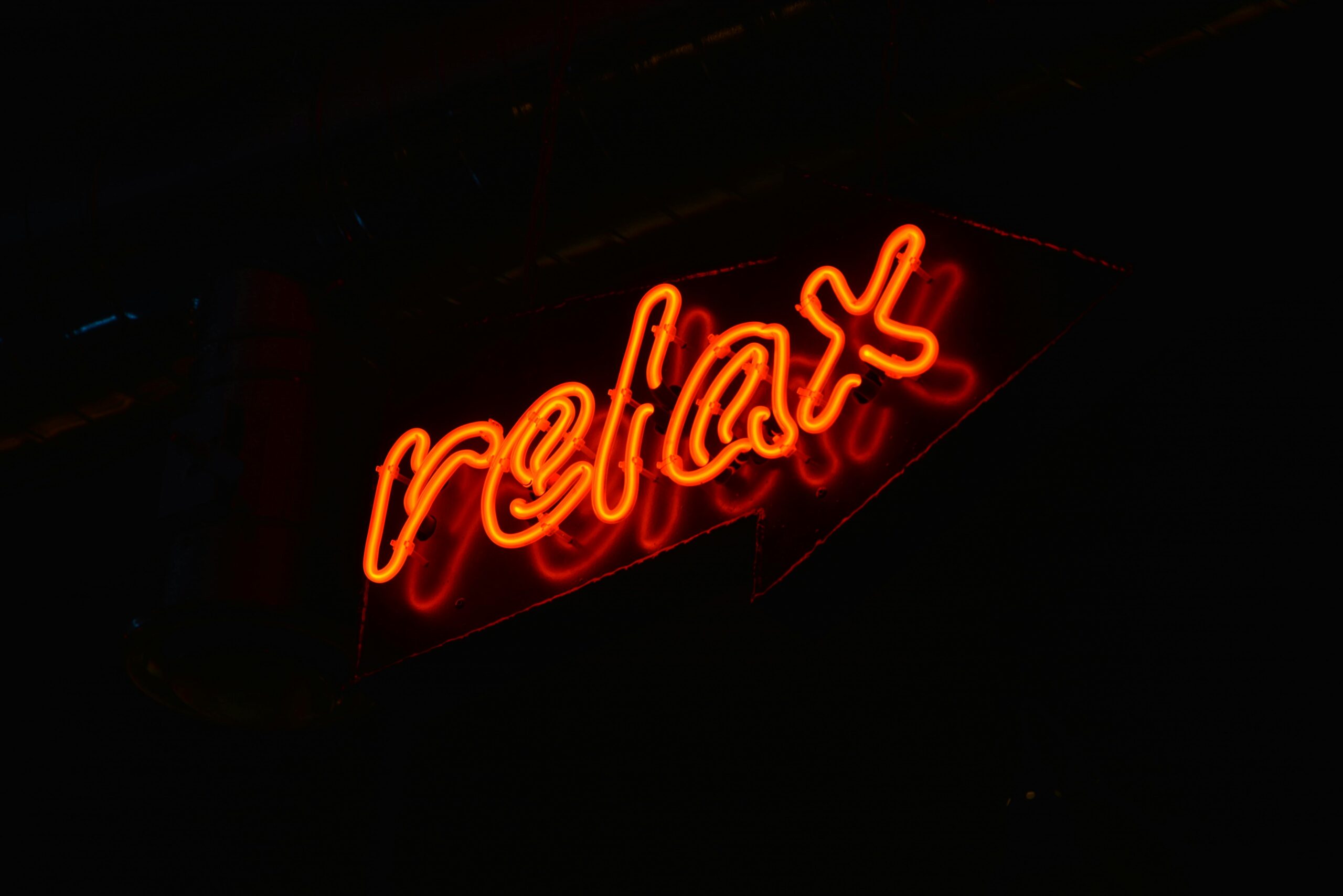 A glowing red neon 'relax' sign against a black background, perfect for modern decor.